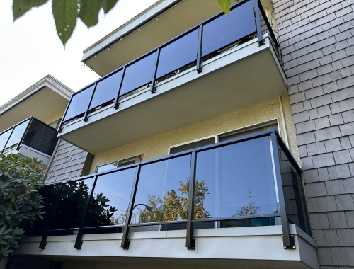 Apartment balconies with dark tinted glass railings with black metal framing