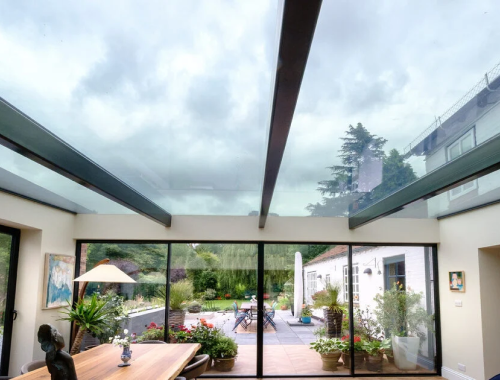 Modern room with large windows and glass ceiling looking out at a yard