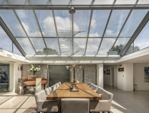 A modern dining room with a large glass roof and ceiling