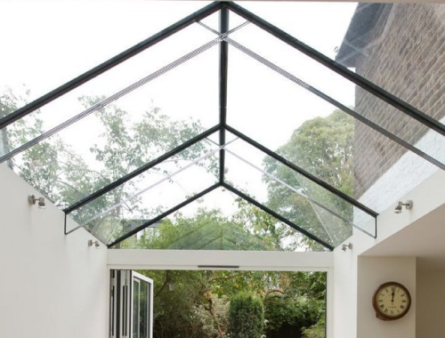 Glass ceiling revealing trees and plant life in a yard