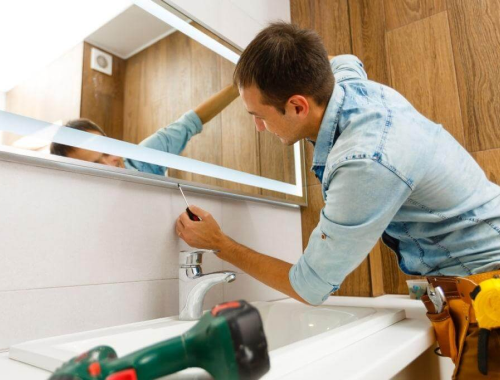 Man installing a mirror in a bathroom