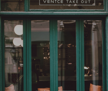 Green storefront building with large windows revealing interrior