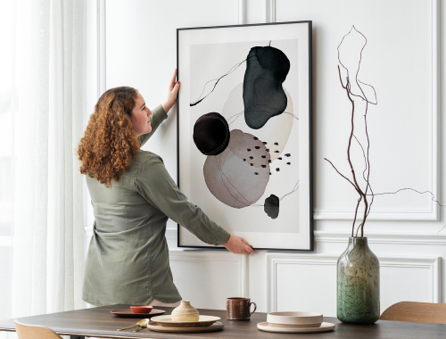 Woman hanging picture of modern artwork