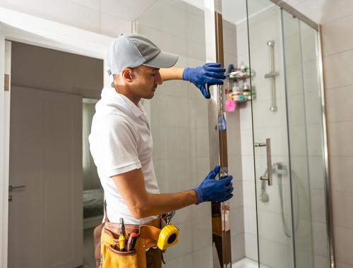 Worker installing mirrors in a bathroom