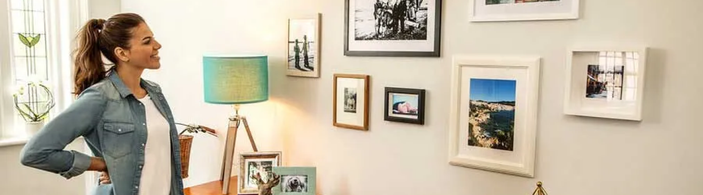 Woman standing back to admire pictures hanging on a wall