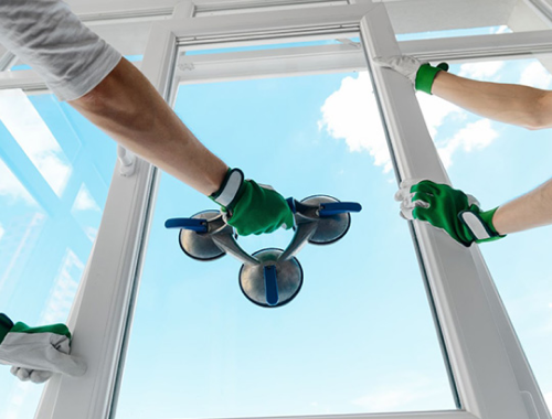 Workers using a tool to install a window pane