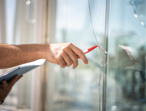 Hand pointing out crack in glass with a pen